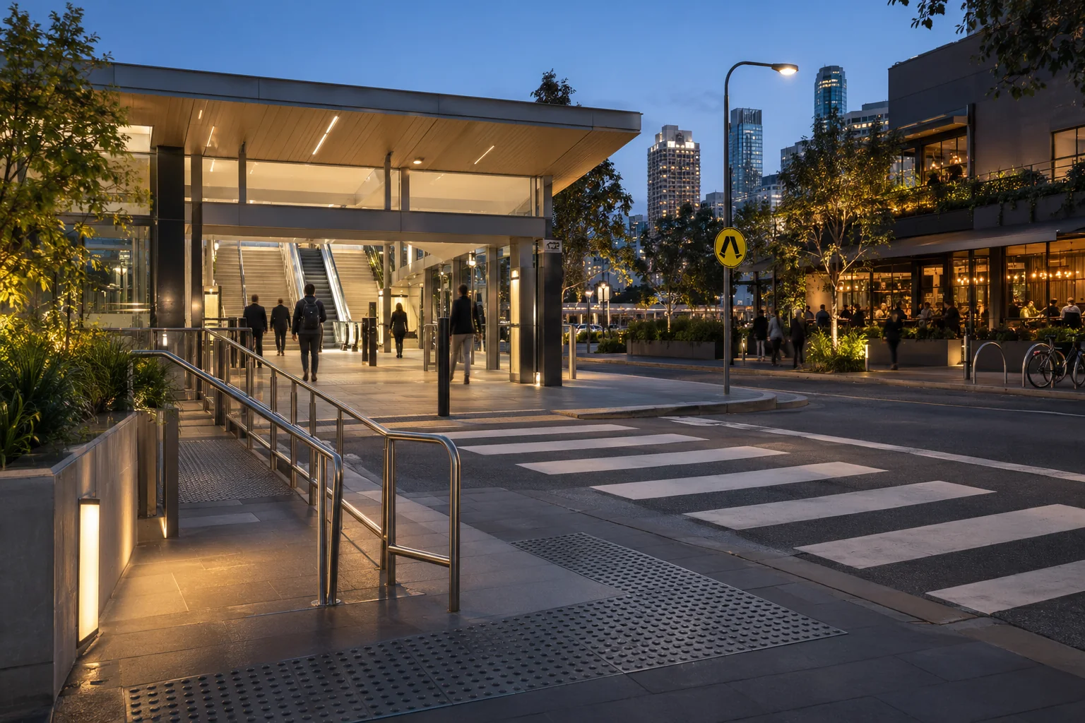 Illustrative accessible station entrance, pedestrian crossing and nearby hospitality venue at blue hour